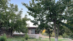 Un muro de piedra, un árbol y un edificio con tejado rojo.