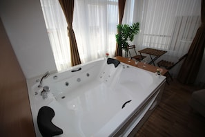 Une salle de bain moderne avec une grande baignoire, une petite table avec des chaises et une plante en pot.