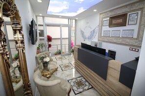 A reception area with a modern desk, a large mirror, and a wall with framed certificates.