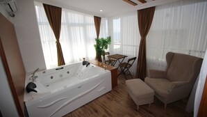 Une salle de bain moderne dotée d’une grande baignoire, d’un plancher en bois et d’un coin salon avec une table et des chaises.