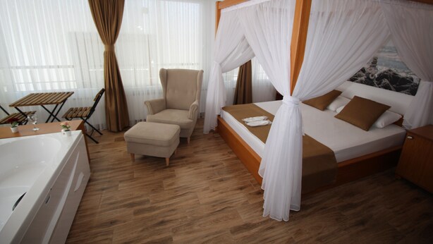 Une chambre à coucher avec un lit à baldaquin, une chaise, une petite table et une baignoire.