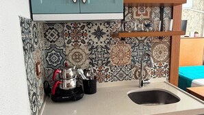 Une cuisine avec des armoires de couleur turquoise, un dosseret à motifs et un réfrigérateur blanc.
