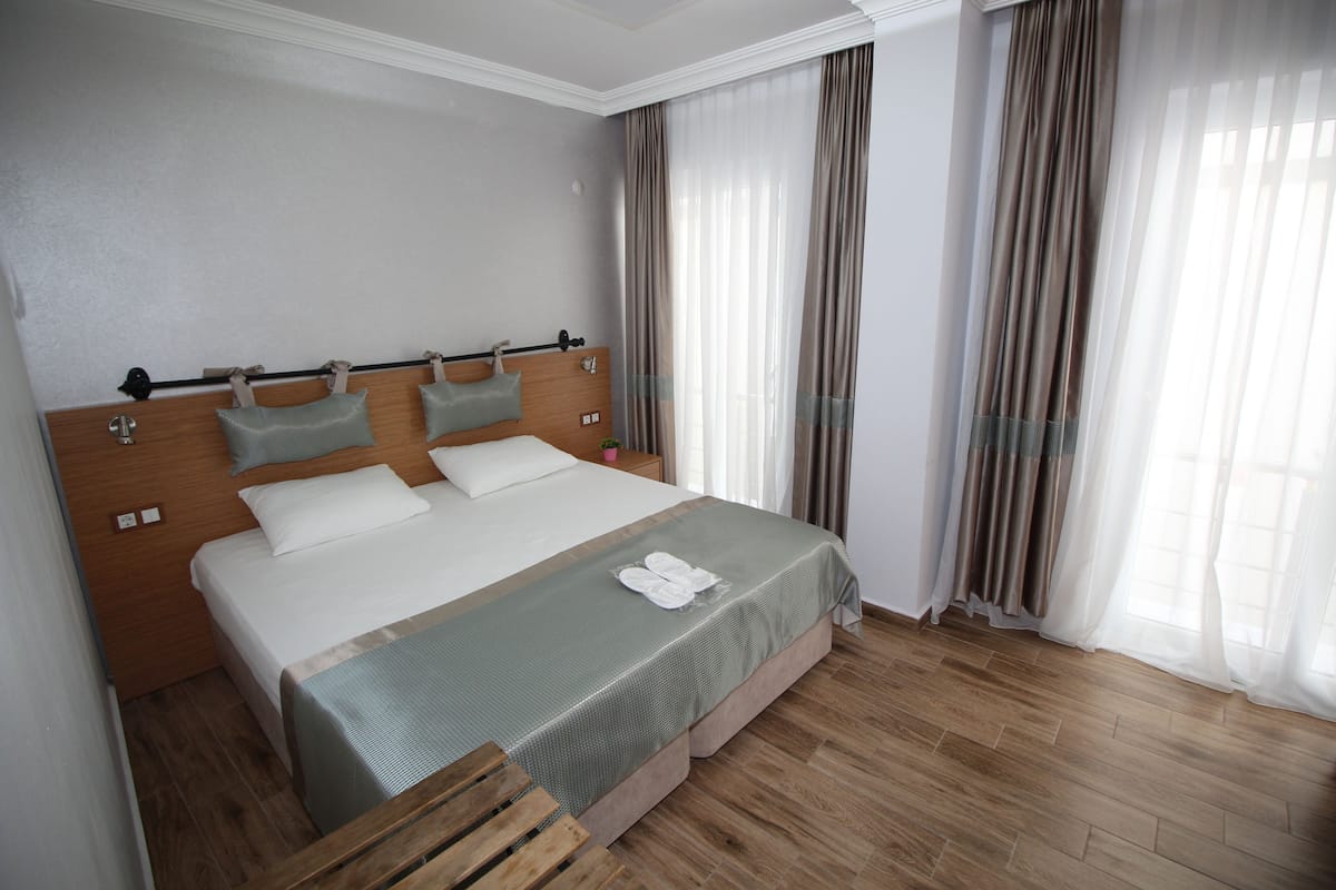 Ein ordentlich eingerichtetes Hotelzimmer mit einem großen Bett, einem hölzernen Kopfteil und einer Holzbank.