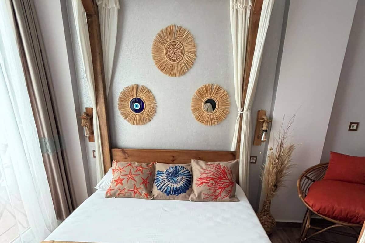 Ein Bett mit Holz-Kopfteil, drei Wanddekorationen und ein roter Stuhl.