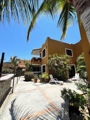 A two-story building with a courtyard, palm trees, and lounge chairs. - Heart of Los Barriles Short Walk to Beach (Los Barriles)