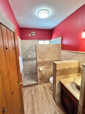 Une salle de bain avec douche, toilettes et lavabo.