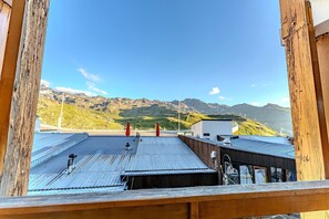A rooftop with a metal roof, a wooden deck, and a view of mountains.