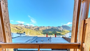 Un balcón de madera con techo metálico que da a un paisaje montañoso.