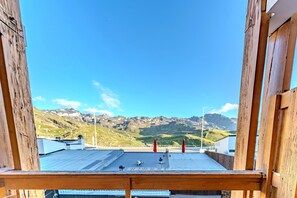 A wooden balcony with a metal roof overlooking a mountainous landscape.