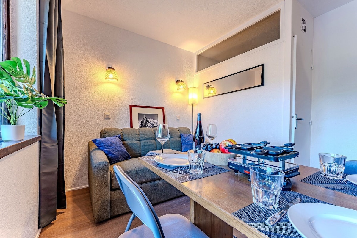 Un comedor con una mesa de madera, sillas, un sofá y una lámpara fijada a la pared.