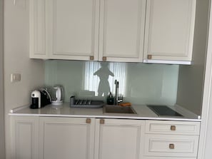 A small kitchenette with a coffee maker, toaster, kettle, and a sink. - Turkuaz Boutique Hotel (Sveti Stefan)