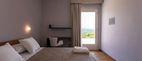 A hotel room with a bed, a desk, a chair, a window with curtains, and a view of the outdoors.