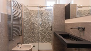 Un baño moderno con ducha, lavamanos y espejo.