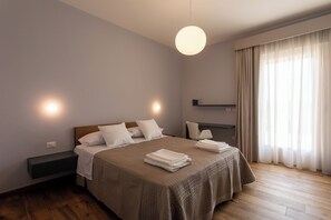 A modern hotel room with a large bed, bedside tables, a mirror, and a view of the outdoors through sheer curtains. - Agriturismo Fontanavecchia (Torrecuso)