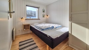 A bedroom with a bed, a window, a bedside table, and a wall-mounted light fixture. - VillaVilla 980 - Juelsminde, Østjylland (Juelsminde)