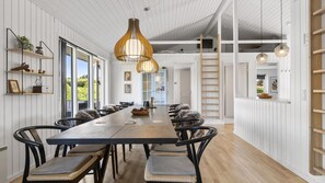 A modern dining area with a long table, black chairs, and pendant lighting. - VillaVilla 980 - Juelsminde, Østjylland (Juelsminde)