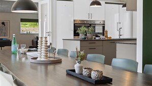 Een moderne keuken met witte kasten, een centraal eiland en hanglampen.