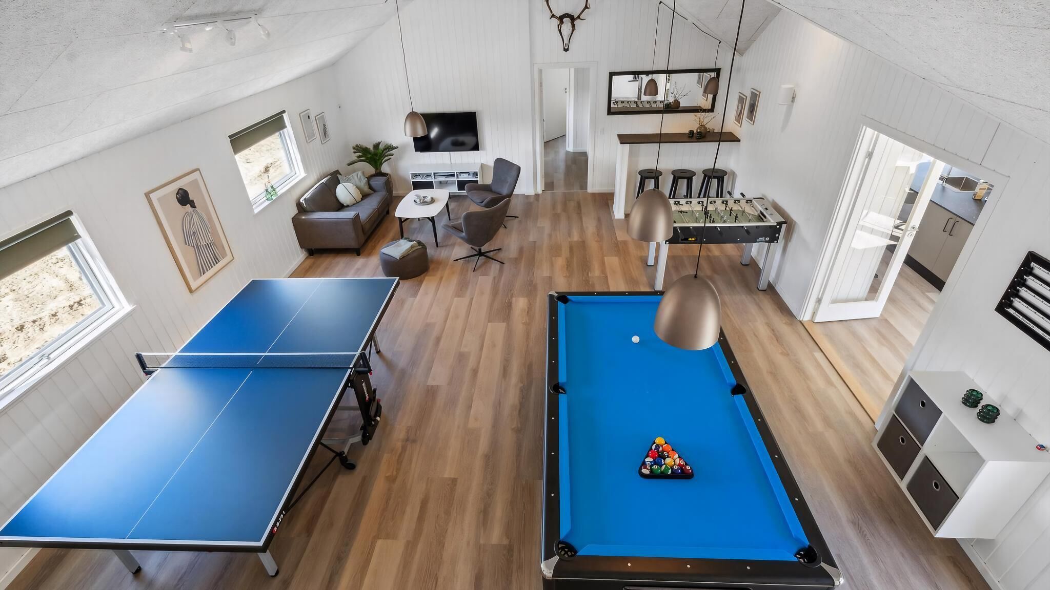 Un salon moderne équipé d’une table de ping-pong, d’un billard et d’un baby-foot.