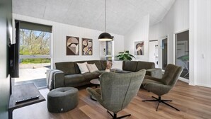 Een moderne woonkamer met een bank, fauteuils, een salontafel en kunstwerken aan de wanden.