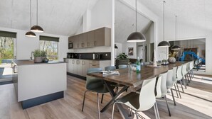 Een moderne keuken met een centraal eiland, een eethoek met stoelen en hangende verlichting.