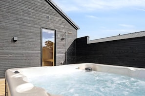 A wooden exterior wall, a glass door, and a hot tub with water. - VillaVilla 962 - Marielyst, Lolland/Falster/møn (Idestrup)