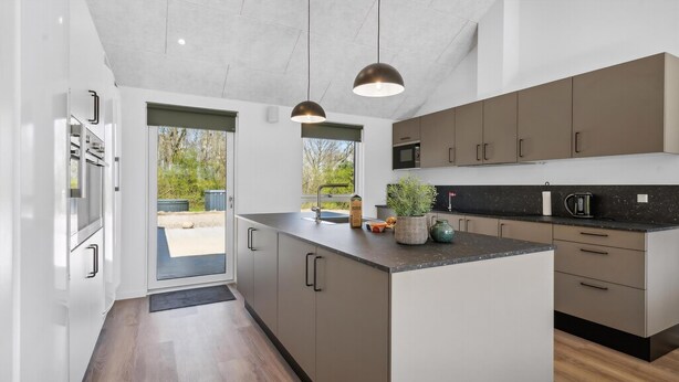 Een moderne keuken met een centraal eiland, inbouwapparatuur en uitzicht op de omgeving.