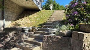 A stone staircase with steps leading up to a building, surrounded by greenery and decorative urns. - House for 8 people in Meymac with electric bikes (Meymac)