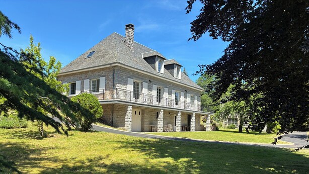 A large stone house with a balcony, surrounded by a well-maintained lawn and trees. - House for 8 people in Meymac with electric bikes (Meymac)