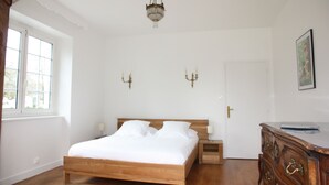 A bedroom with a wooden bed, bedside tables, a dresser, a chandelier, and a door. - House for 8 people in Meymac with electric bikes (Meymac)