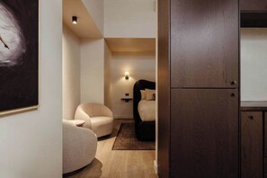 Ein modernes Schlafzimmer mit einem Bett, einem Sessel, einer Wandleuchte und einem Holzschrank.