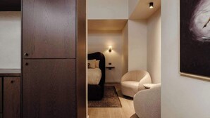 Ein Schlafzimmer mit Bett, Stuhl, Nachttisch und einer Wandlampe.