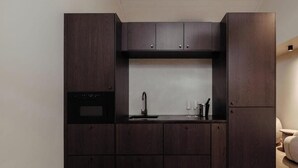 Eine kleine Küche mit dunklen Holzschränken, einem schwarzen Backofen und einem Spülbecken mit Armatur.