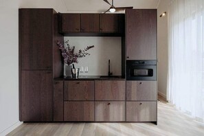 Eine moderne Küche mit dunklen Holzschränken, einem Einbauofen und einer Vase mit Blumen.
