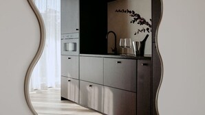 Une cuisine moderne dotée d’appareils électroménagers en acier inoxydable, d’un plan de travail foncé et d’un miroir décoratif.