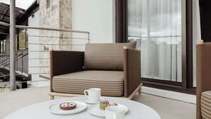 Un espace détente moderne avec un fauteuil confortable, une table ronde recouverte d’une nappe blanche et une fenêtre donnant sur un beau paysage.
