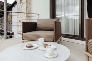 Ett modernt loungeområde med en bekväm fåtölj, ett runt bord med ett vitt bordsduks och ett fönster med utsikt.