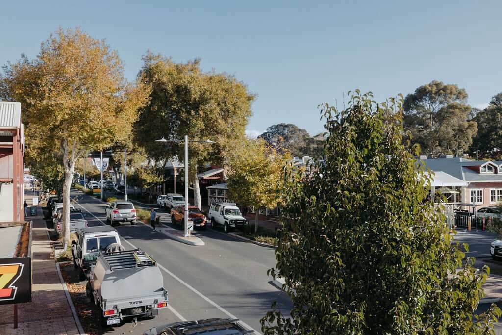 Une vue de rue avec des véhicules garés, des arbres et des bâtiments.