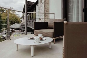 Ein Balkon mit einem weißen Tisch, zwei Stühlen und einer Sitzecke.