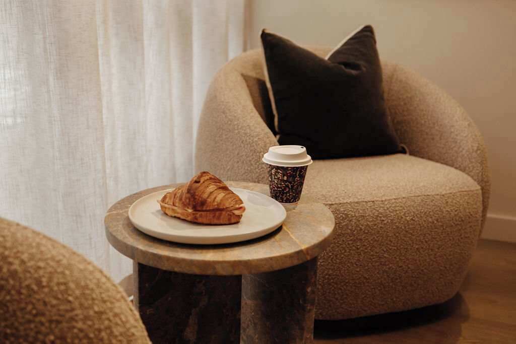 Un coin salon confortable avec une table ronde, une assiette contenant un croissant et une tasse de café.