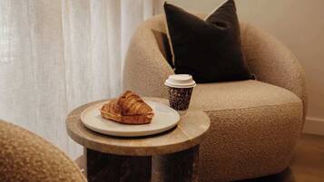 Un coin salon confortable avec une table ronde, une assiette contenant un croissant et une tasse de café.