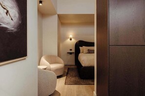 Une chambre à coucher avec un lit, une chaise, une lampe fixée au mur et un tableau.