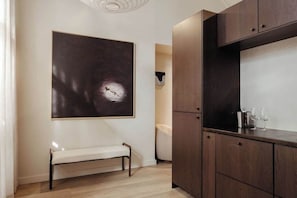 Ein modernes Interieur mit einer Bank, einem großen abstrakten Gemälde und einem Holzkabinett mit Gläsern.