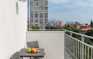 Ein Balkon mit Tisch und Stuhl, einer Obstplatte und Blick auf Gebäude und Berge.