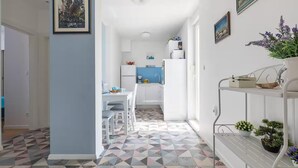 Eine moderne Küche mit weißen Schränken, einer blauen Spritzschutzwand und einem Essbereich mit weißem Tisch und Stühlen.