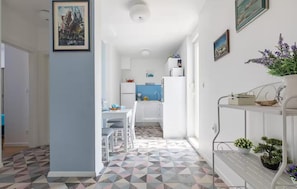 A modern kitchen with white cabinets, a blue backsplash, and a dining area with a white table and chairs. - Amazing apartment in Split with house sea view (Split)