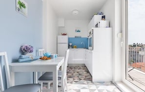 A compact kitchen with a dining area, a refrigerator, and a window with a view of buildings. - Amazing apartment in Split with house sea view (Split)