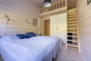 A wooden cabin bedroom with a bed, two pillows, a wardrobe, a mirror, a ceiling light, and a wooden ladder. - Villa Hellitä | Peaceful 3BR Villa with Hot Tub (Ylläsjärvi)