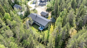 Une cabane entourée d’une forêt dense, avec un jacuzzi visible et une vue dégagée sur les arbres environnants.
