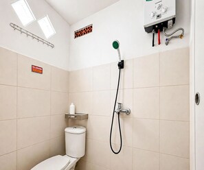 Ein kleines Badezimmer mit Toilette, Dusche und einem Schild mit der Zimmernummer.