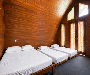 Ein Zimmer mit Holzwänden, drei Betten und einer geneigten Decke.
